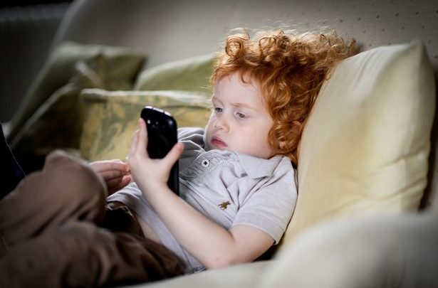 Young child using phone - مدونة التقنية العربية